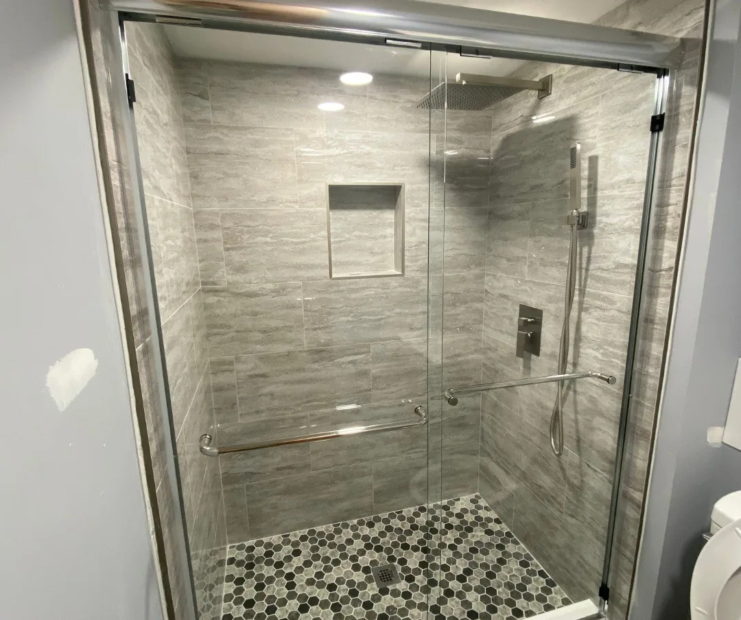 Frameless glass walk-in shower with large format tile and pebble mosaic floor