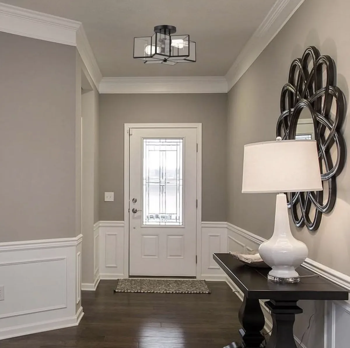 Entryway painted in warm gray with white wainscoting, trim, and a console table