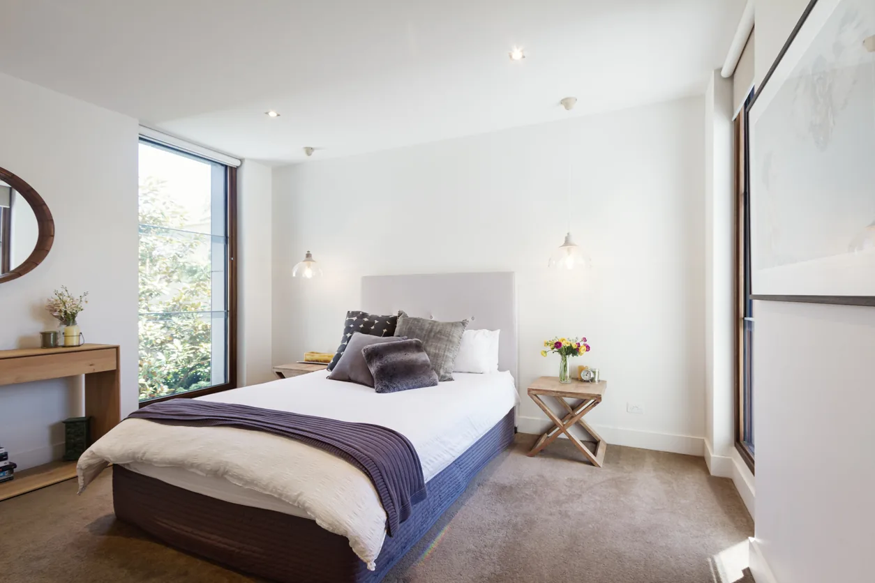 Modern basement bedroom with pendant lights and floor-to-ceiling windows