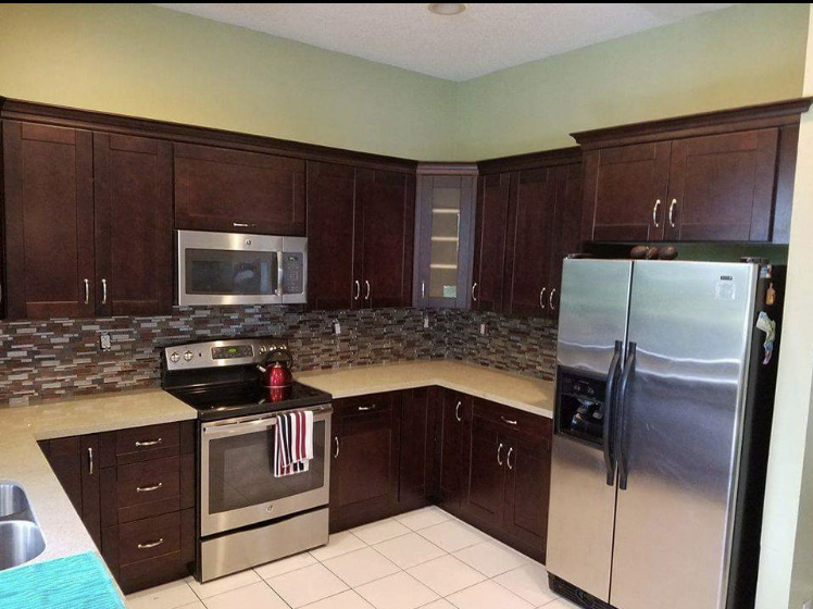 Kitchen renovation using dark cabinetry, granite countertop, and backsplash.